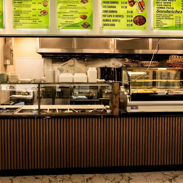A restaurant counter with food warmers, a display case, and menu boards above.