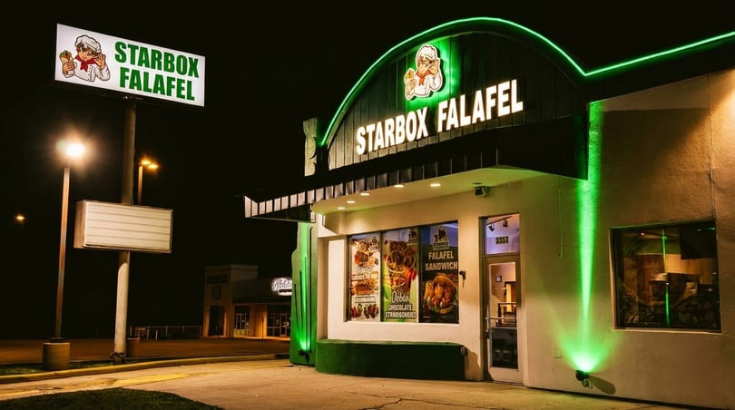 Starbox Falafel restaurant exterior at night, illuminated by green neon lights and streetlights.
